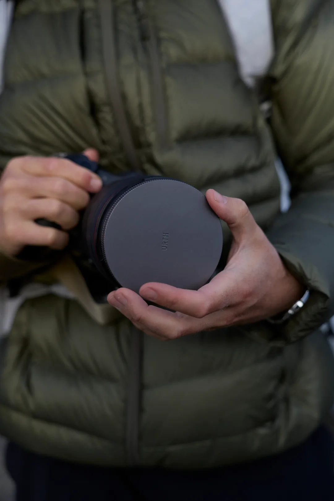Hands holding a filter case with URTH stamped on it