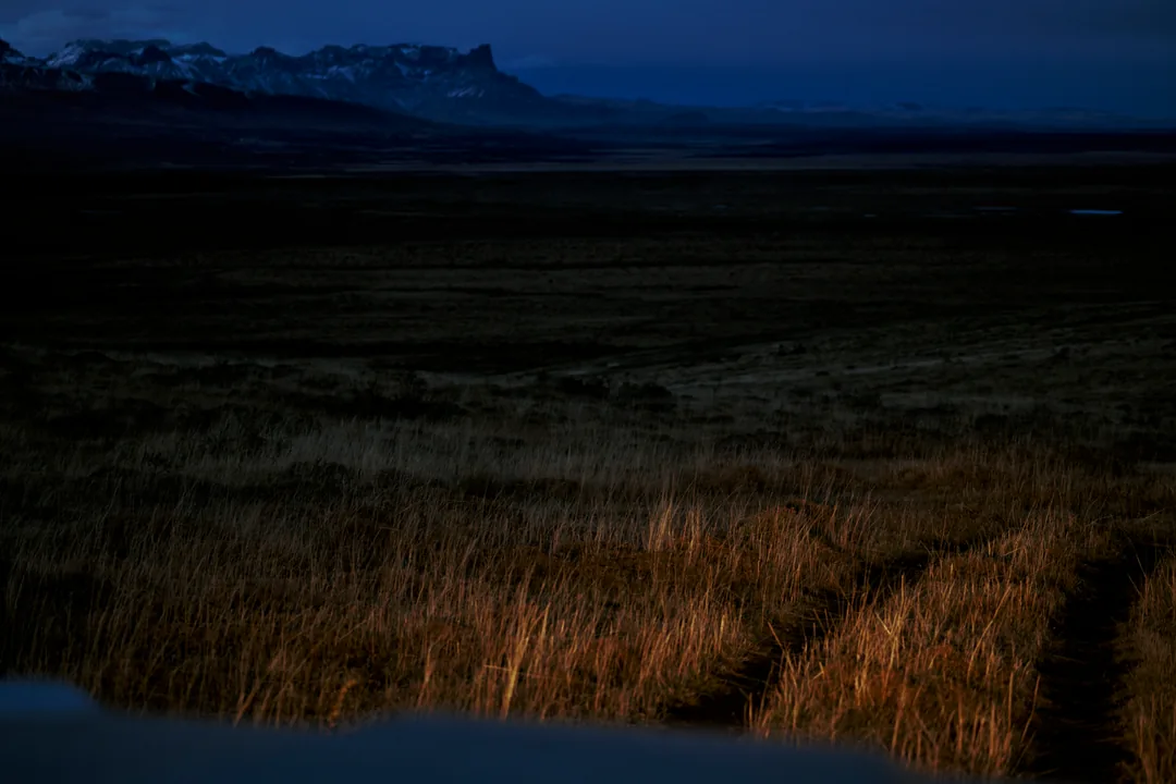 A wide empty plain at blue hour under a distant snow ridge